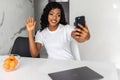 Happy beautiful African American woman taking selfie on mobile phone camera,. Emotional blogger streaming video online, Royalty Free Stock Photo