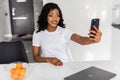 Happy beautiful African American woman taking selfie on mobile phone camera,. Emotional blogger streaming video online, Royalty Free Stock Photo