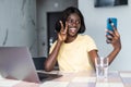 Happy beautiful African American woman taking selfie on mobile phone camera, showing victory sign. Emotional blogger streaming Royalty Free Stock Photo