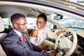 Beautiful african couple is choosing new car at dealership.