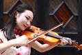 Happy beautiful Asian Chinese woman artist in traditional chi-pao cheongsam play violin in a garden close-up Royalty Free Stock Photo