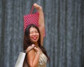 Happy and beautiful Asian Chinese woman walking on the street posing on background smiling cheerful carrying shopping bag Royalty Free Stock Photo