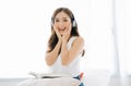 Happy beautiful Asian girl joyful listening to music using wireless earphones and holding her cheeks with a laugh looking to Royalty Free Stock Photo