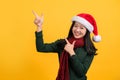 Happy beautiful Asian girl wearing colorful Christmas attire pointing hands to empty space aside isolated on yellow background Royalty Free Stock Photo