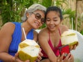 Happy and beautiful Asian Indonesian teenager girl taking selfie with mobile phone enjoying holidays drinking coconut at tropical Royalty Free Stock Photo