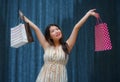 Happy and beautiful Asian Korean woman walking on the street posing on background smiling cheerful carrying shopping bags Royalty Free Stock Photo