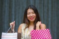 Happy and beautiful Asian Korean woman walking on the street posing on background smiling cheerful carrying shopping bags Royalty Free Stock Photo