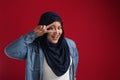 Happy beautiful Asian muslim woman posing in front of camera and smiling, showing peace victory hand sign Royalty Free Stock Photo