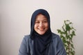 Happy beautiful Asian muslim woman wearing hijab looking at camera and smiling, cheerful friendly expression