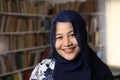 Happy beautiful Asian muslim woman wearing hijab smiling to camera, female student in library Royalty Free Stock Photo
