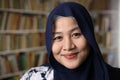 Happy beautiful Asian muslim woman wearing hijab smiling to camera, female student in library Royalty Free Stock Photo