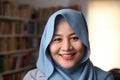 Happy beautiful Asian muslim woman wearing hijab smiling to camera, female student in library Royalty Free Stock Photo