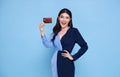 Happy beautiful Asian shopaholic women wearing blue dress showing credit card in hand isolated on blue background