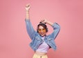Happy beautiful Asian teen woman in yellow glasses listening music in headphones and dance on pink background Royalty Free Stock Photo