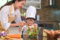 Happy beautiful Asian woman and cute little boy with eyeglasses prepare to cooking in kitchen at home. People lifestyles and