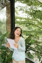 Happy Beautiful Asian Woman holding book or diary on green natural outdoor background Royalty Free Stock Photo