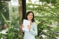 Happy Beautiful Asian Woman holding book or diary on green natural outdoor background Royalty Free Stock Photo