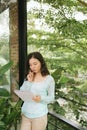 Happy Beautiful Asian Woman holding book or diary on green natural outdoor background Royalty Free Stock Photo