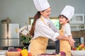 Happy beautiful Asian woman dress up cute little boy chef outfit for prepare to cooking in home kitchen. People lifestyles and Royalty Free Stock Photo