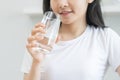 Happy beautiful, asian young woman hand in holding, drinking fresh glass of water for hydration of body, holding transparent glass Royalty Free Stock Photo
