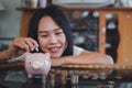 Happy beautiful asian young woman and hand putting coin into piggy bank, Finance or Savings concept. Royalty Free Stock Photo