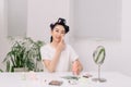 Happy beautiful asian young woman looking in to mirror, holding cotton pad, applying facial wipe on her face Royalty Free Stock Photo