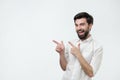 Happy beautiful bearded guy looking at camera, smiling and pointing aside with hand.