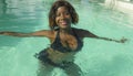 Happy and beautiful black African American woman in bikini having fun at tropical beach resort swimming pool relaxed and playful Royalty Free Stock Photo