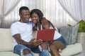 Happy beautiful black afro American couple in love enjoying at living room sofa couch with laptop computer having fun with Royalty Free Stock Photo