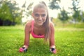 Happy, beautiful blonde girl doing abs and isometry on grass