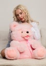 Happy beautiful blonde woman hugging a teddy bear. Concept of holiday or birthday Royalty Free Stock Photo