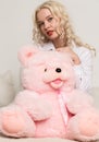Happy beautiful blonde woman hugging a teddy bear. Concept of holiday or birthday Royalty Free Stock Photo