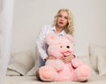 Happy beautiful blonde woman hugging a teddy bear. Concept of holiday or birthday Royalty Free Stock Photo