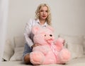 Happy beautiful blonde woman hugging a teddy bear. Concept of holiday or birthday Royalty Free Stock Photo