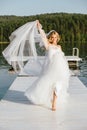 Happy beautiful bride in a chic white wedding dress and veil, smiling barefoot, runs towards happiness Royalty Free Stock Photo