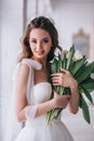 Happy beautiful bride holding wedding bouquet of white tulips in her hands in studio. Royalty Free Stock Photo