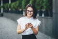 Happy beautiful business woman walking and writing or reading sms messages on line on a smart phone while the wind moves Royalty Free Stock Photo