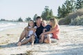 Happy beautiful Caucasian family having holidays on the beach smiling with mother and father sitting on sand with little son and y Royalty Free Stock Photo