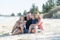 Happy beautiful Caucasian family having holidays on the beach smiling with mother and father sitting on sand with little son and y Royalty Free Stock Photo