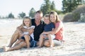 Happy beautiful Caucasian family having holidays on the beach smiling with mother and father sitting on sand with little son and y Royalty Free Stock Photo