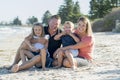 Happy beautiful Caucasian family having holidays on the beach smiling with mother and father sitting on sand with little son and y Royalty Free Stock Photo