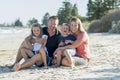 Happy beautiful Caucasian family having holidays on the beach smiling with mother and father sitting on sand with little son and y Royalty Free Stock Photo