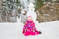 Happy beautiful child girl plaing with a snowman on snowy winter walk.