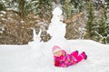 Happy beautiful child girl plaing with a snowman on snowy winter walk. Royalty Free Stock Photo