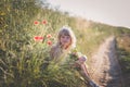 happy beautiful child outdoors in countryside sitting in grass with red poppy flowers Royalty Free Stock Photo