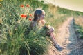 happy beautiful child outdoors in countryside sitting in grass with red poppy flowers Royalty Free Stock Photo