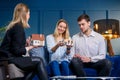 Happy beautiful couple discussing design of house with young female designer in the blue office. Royalty Free Stock Photo