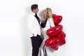 Happy beautiful couple posing on white background and holding balloons heart. Valentine`s day. Royalty Free Stock Photo