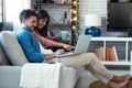 Happy beautiful couple using computer while sitting on the couch at home Royalty Free Stock Photo