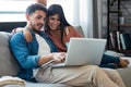 Happy beautiful couple using computer while sitting on the couch at home Royalty Free Stock Photo